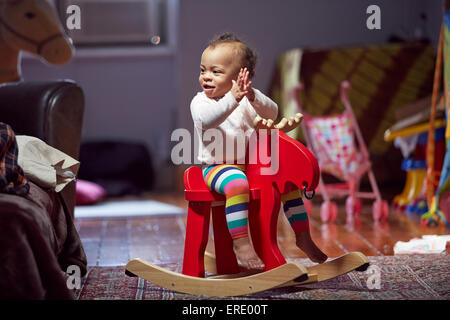 Gemischte Rassen Babymädchen spielen auf Schaukelpferd Stockfoto