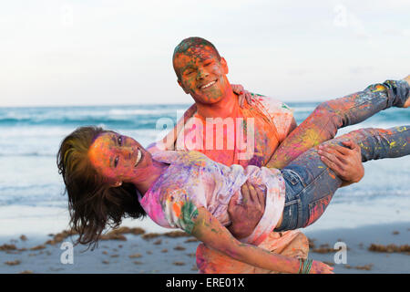 Kaukasische paar spritzte mit Farbe Pulver am Strand Stockfoto