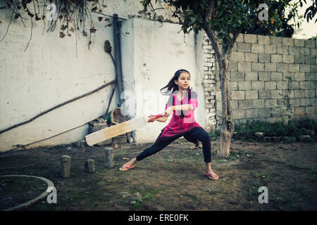 Gemischte Rassen Mädchen spielen Cricket in der Nähe von Wand Stockfoto