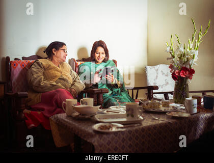 Mutter und Tochter mit Handy am Esstisch Stockfoto