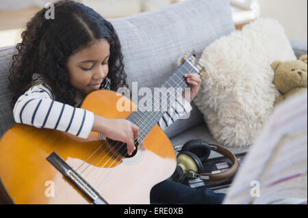 Gemischte Rassen Mädchen üben Gitarre auf sofa Stockfoto