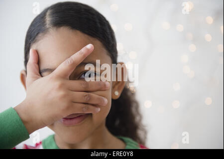 Nahaufnahme von Mischlinge Mädchen spähen zwischen den Fingern Stockfoto