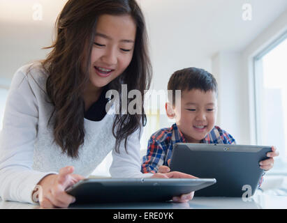 Asiatische Bruder und Schwester, die mit digitalen Tabletten am Tisch Stockfoto