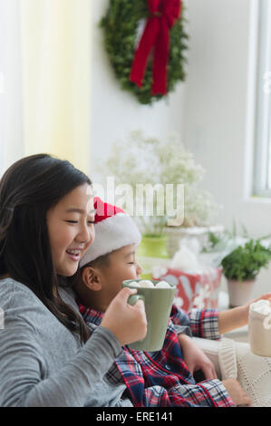 Asiatische Bruder und Schwester trinken heiße Schokolade zu Weihnachten Stockfoto