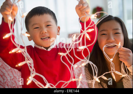 Asiatische Kinder spielen mit Weihnachten Lichterkette Stockfoto