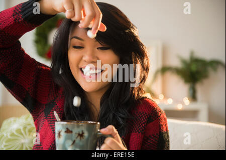 Pacific Islander Frau Fallenlassen Marshmallows in heiße Schokolade Stockfoto