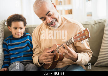 Gemischte Rassen Großvater und Enkel, die Ukulele zu spielen Stockfoto