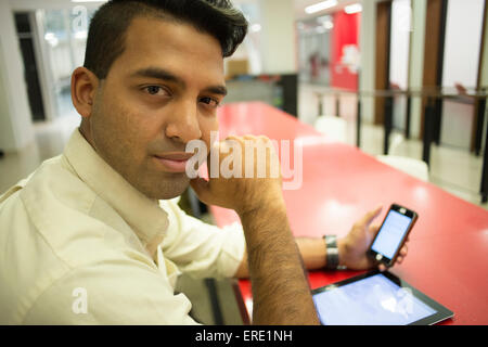 Asiatische Geschäftsmann mit Handy und digital-Tablette in office Stockfoto