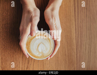 Hände halten Tasse Kaffee mit Milch angesaugt Blatt Stockfoto