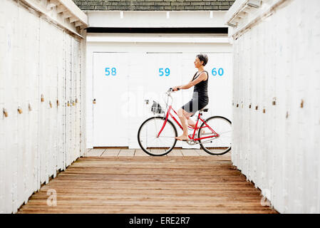 Ältere kaukasischen Frau Reiten Fahrrad auf hölzerne dock Stockfoto