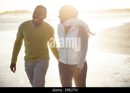 Lächelnde paar zu Fuß am Strand Stockfoto