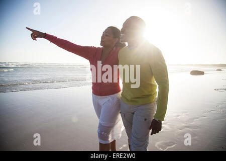 Lächelnde paar zu Fuß am Strand Stockfoto
