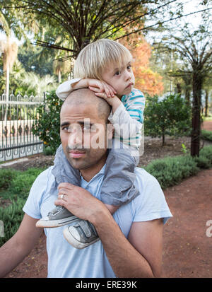 Hispanische Vater mit Sohn auf Schultern im park Stockfoto