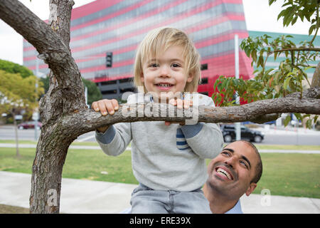 Hispanische Vater und Sohn spielen auf Baum im park Stockfoto