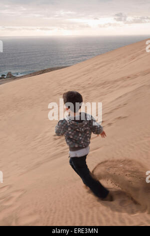 Hispanische junge laufen auf Sand Düne am Strand Stockfoto
