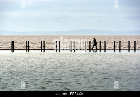 Walk the Line. Eine Person geht über den Damm trennt den Marine-See vom Meer im Weston-super-Mare. Stockfoto