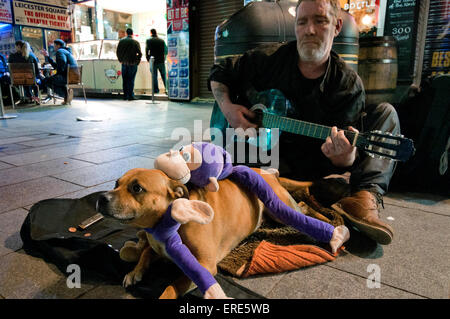 Obdachlosen Mann als Straßenmusikant und Gitarre in Soho mit seinem Hund zu spielen. Stockfoto