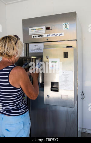 Frau frischen Milch aus dem Automaten auf einem Milchviehbetrieb in Cable Bay, Neuseeland zu kaufen. Stockfoto