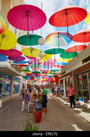 Bunte Schirme hängen über den Geschäften einer Straße in Paspatur