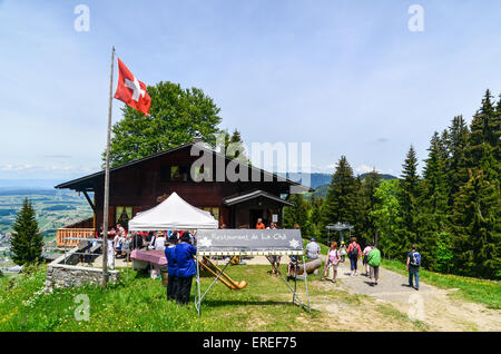 Traditionelle Musiker spielen cor des Alpes (Alphorn) in der Schweiz, einem Café mit Touristen Stockfoto