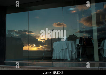 Eine leere Tabelle in einem Restaurant mit die untergehende Sonne spiegelt sich im Fenster Stockfoto