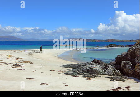 Mann zu Fuß in Richtung seiner Jolle auf den wunderschönen weißen Sandstrand von Eilean Annraidh (Insel des Sturms) nördlich von Iona in Schottland Stockfoto