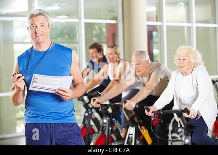 Fitness-Trainer mit Senioren auf spinning Bikes im Fitness-Studio Stockfoto