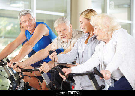 Trainer mit Stoppuhr, senior Group auf spinning Bikes im Fitness-Studio Stockfoto