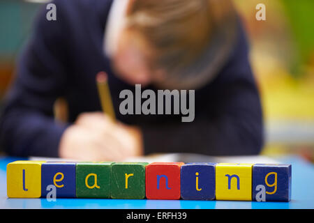 Wort "Lernen" Dinkel In Holzblöcke mit Schüler hinter Stockfoto