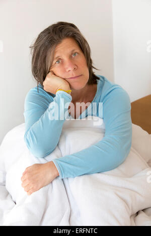 ältere Frau im Bett sitzen und schauen traurig Stockfoto