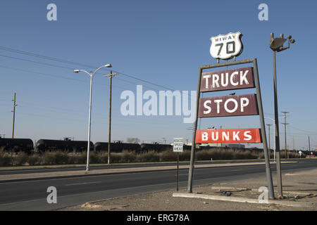 Vintage Autohof mitsingen Highway 70 im ländlichen New Mexiko mit Öltankern im Hintergrund. Stockfoto