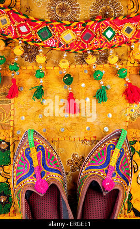 Bunten ethnischen Schuhe und Gipsy Gürtel auf gelben Kissenhülle aus Rajasthan am Flohmarkt in Indien Stockfoto