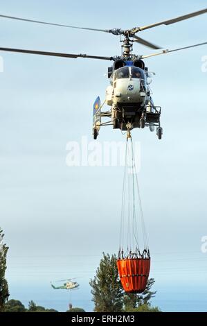 Kamov Ka-32A11BC Hubschrauber (Registrierung EG-JSQ) sammeln Wasser zur Brandbekämpfung von einem Golfplatz See Cabopino Golf. Stockfoto