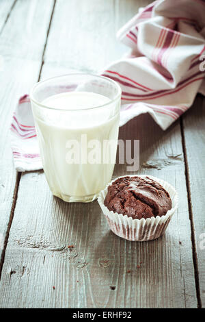 Ein Glas Milch und Schokolade Muffin auf Holztisch Stockfoto