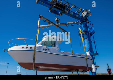 Kleines Motorboot aus dem Wasser gehoben wird, mit einem Schiffshebewerk am Kai bereit für die Wartung durchgeführt werden. Stockfoto