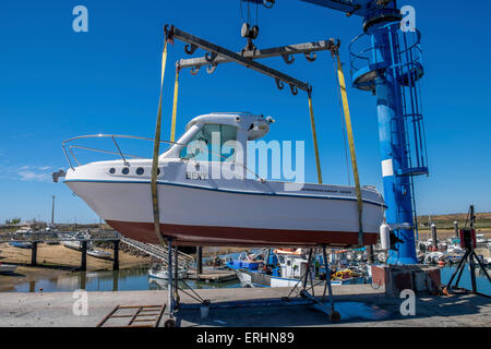 Kleines Motorboot aus dem Wasser gehoben wird, mit einem Schiffshebewerk am Kai bereit für die Wartung durchgeführt werden. Stockfoto