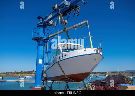 Kleines Motorboot aus dem Wasser gehoben wird, mit einem Schiffshebewerk am Kai bereit für die Wartung durchgeführt werden. Stockfoto