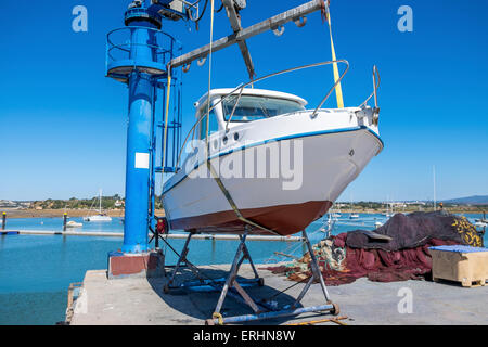 Kleines Motorboot aus dem Wasser gehoben wird, mit einem Schiffshebewerk am Kai bereit für die Wartung durchgeführt werden. Stockfoto