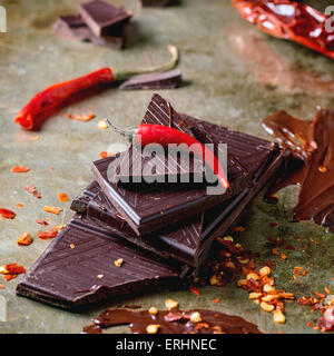 Hacken und schmelzen dunklen Schokolade mit frische und trockene rote scharfe Chilischoten in alten Metall-Hintergrund Stockfoto