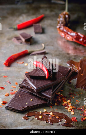 Hacken und Schmelzen von dunkler Schokolade mit frischen und trockenen roten hot Chili Peppers über alte Metall Hintergrund. Selektiven Fokus. Stockfoto