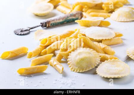 Hausgemachte Ravioli und Garganelli Nudeln mit Mehl und hölzerne Walze über hölzerne hellblauen Hintergrund Stockfoto