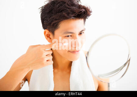 lächelnder Mann Creme eincremen auf Gesicht Stockfoto