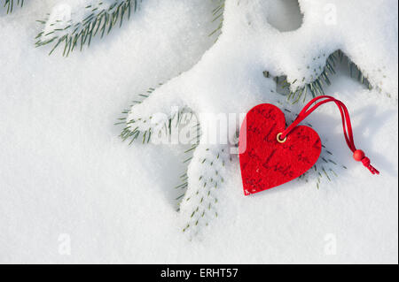 rotes Herz Spielzeug im Schnee auf Tanne Stockfoto