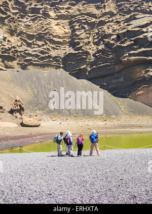 Gruppe der Wanderer in der Nähe von grünen Lagune Charco de Los Clicos, unter vulkanischen Klippen in El Golfo auf Lanzarote, Kanarische Inseln, Spanien Stockfoto