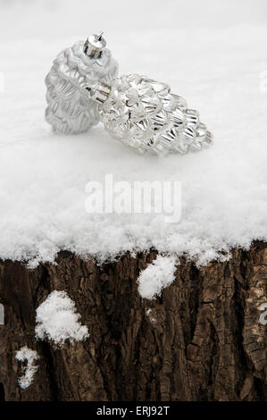 zwei Spielzeug-Zapfen an einem Baum Baumstumpf im Schnee Stockfoto