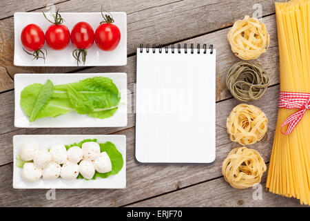 Tomaten, Mozzarella, Nudeln und grüner Salat Blätter auf Holztisch Hintergrund mit dem Editor für Textfreiraum Stockfoto