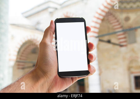 Hand mit Smartphone mit weißen leeren Bildschirm mock-up in der Moschee. Stockfoto