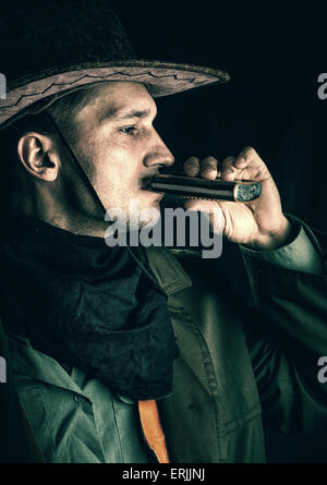 Junge schöne Cowboy in braunen Hut, Alkohol zu trinken aus einer Flasche auf einem schwarzen Hintergrund Stockfoto