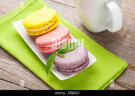 Bunte Macaron Cookies und Tasse Milch auf Holztisch Hintergrund Stockfoto