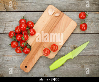 Cherry-Tomaten mit Messer auf Messers Schneide an Bord über Holztisch Hintergrund Stockfoto